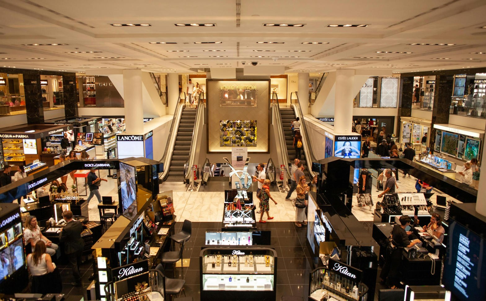 Luxury department-store hall — brands, escalators, till